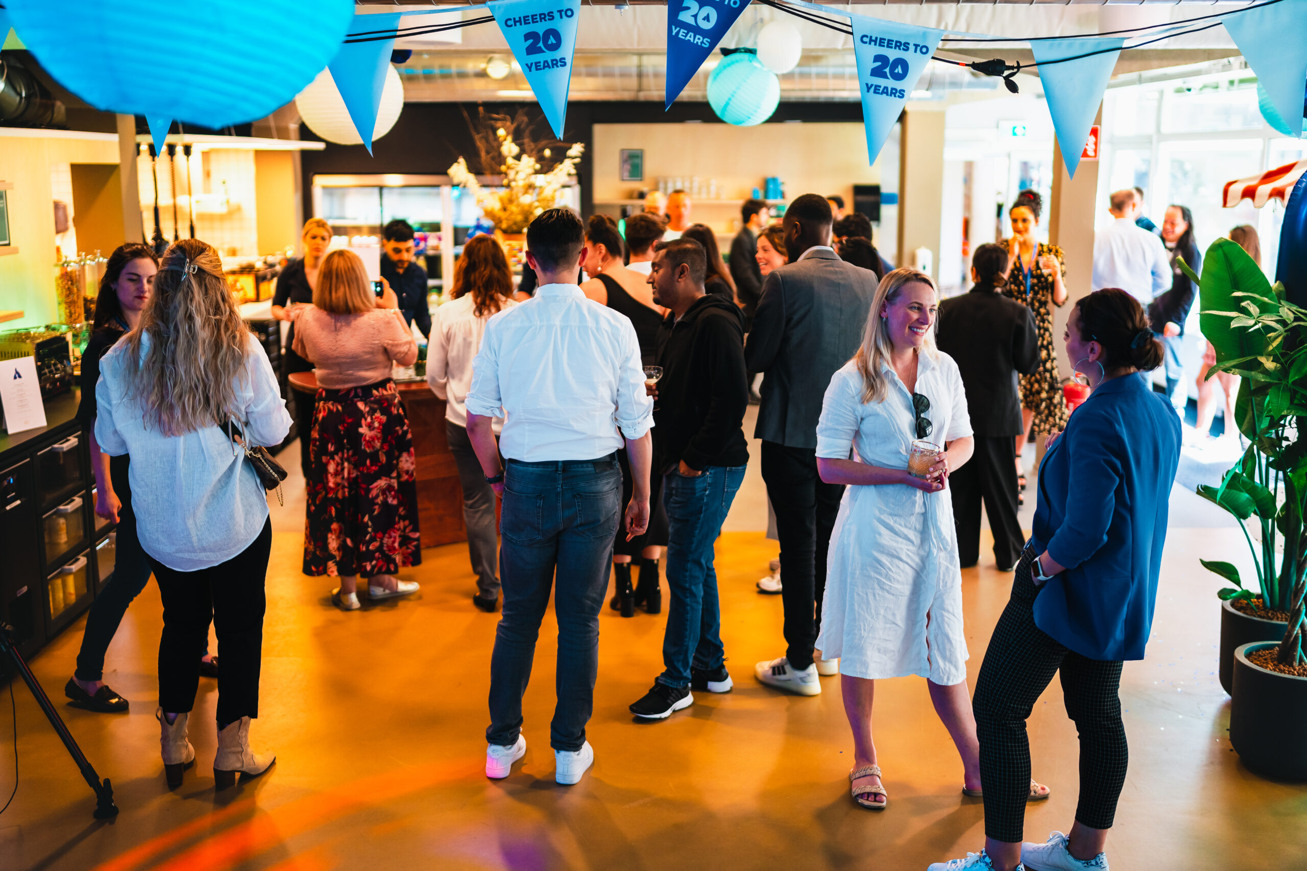 Bedrijfsfeest op eigen locatie - Mensen verzamelen zich tijdens een informeel jubileumevenement met feestelijke decoraties en een ontspannen sfeer.